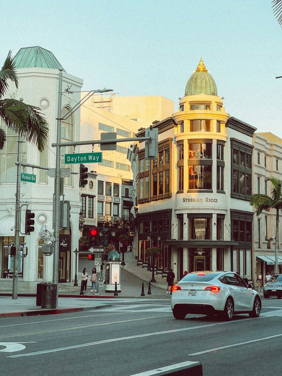 A car driving down a street next to tall buildings on Rodeo Drive in Beverly Hills